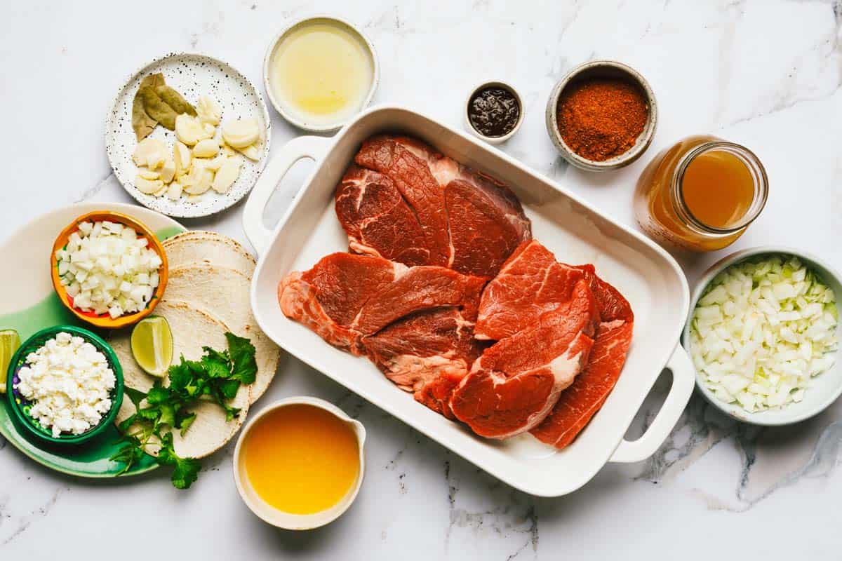 Bowls of ingredients to make shredded beef tacos. 