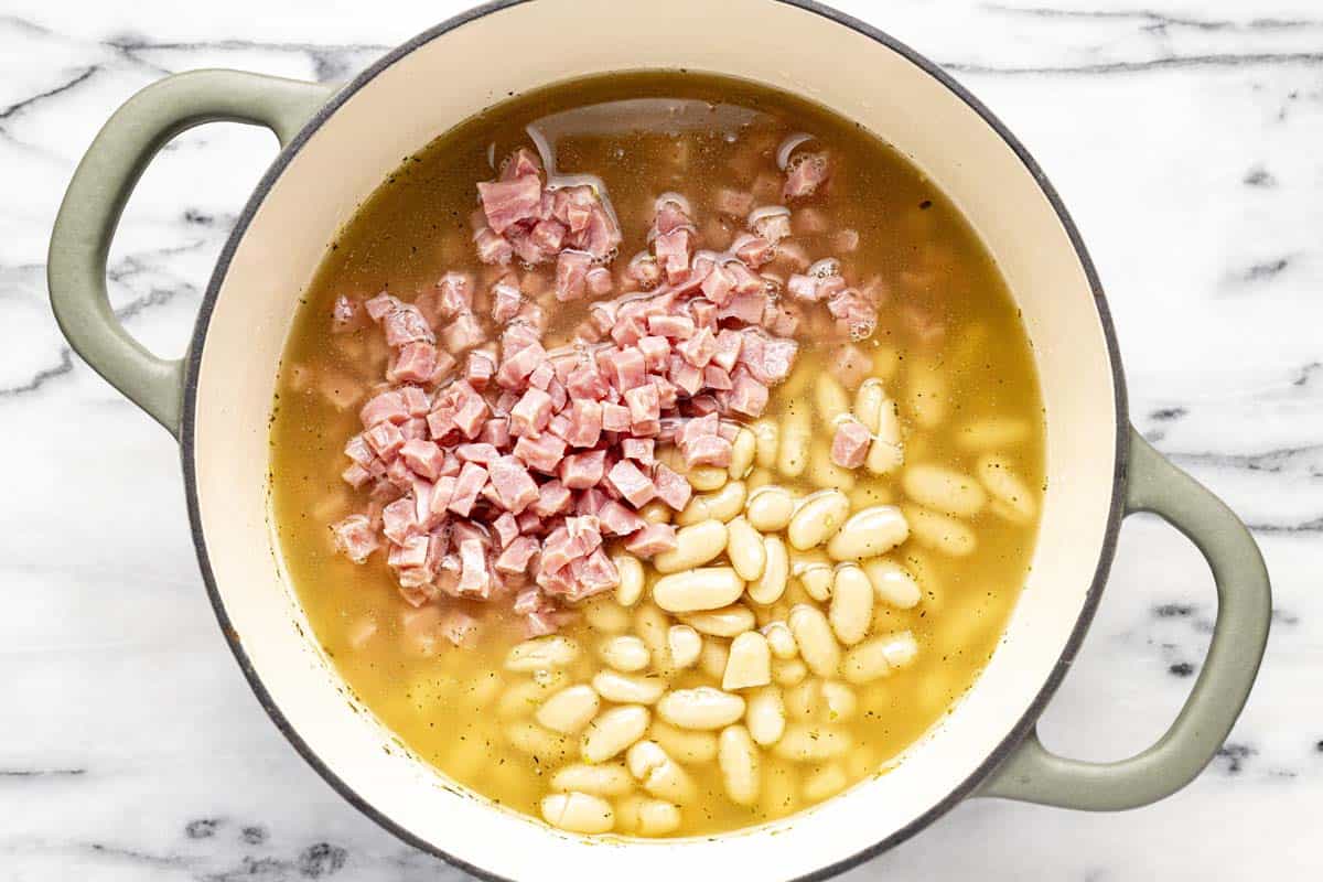 Large pot filled with broth, ham, and beans. 