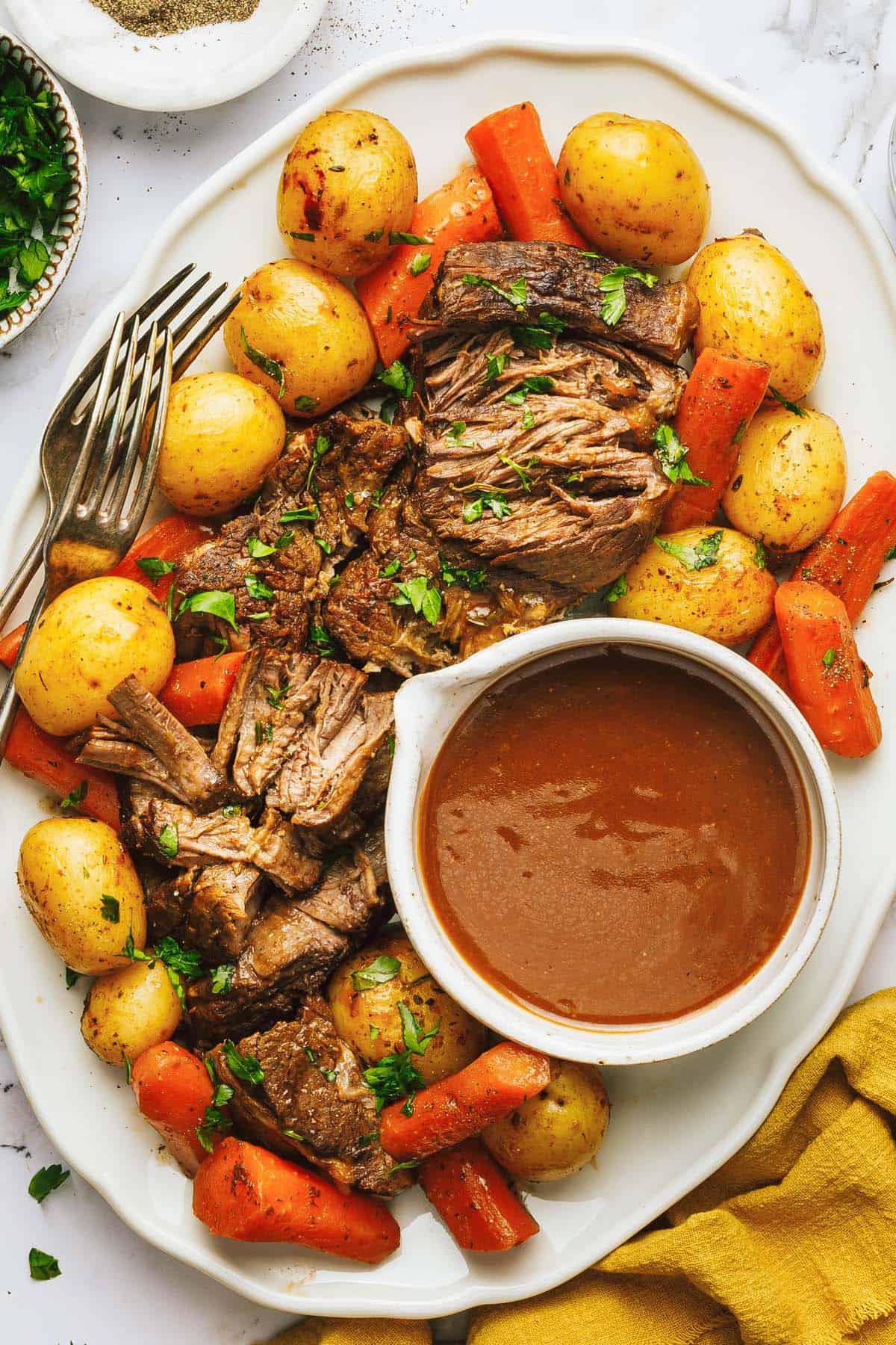 Large serving platter with pot roast and gravy on it. 