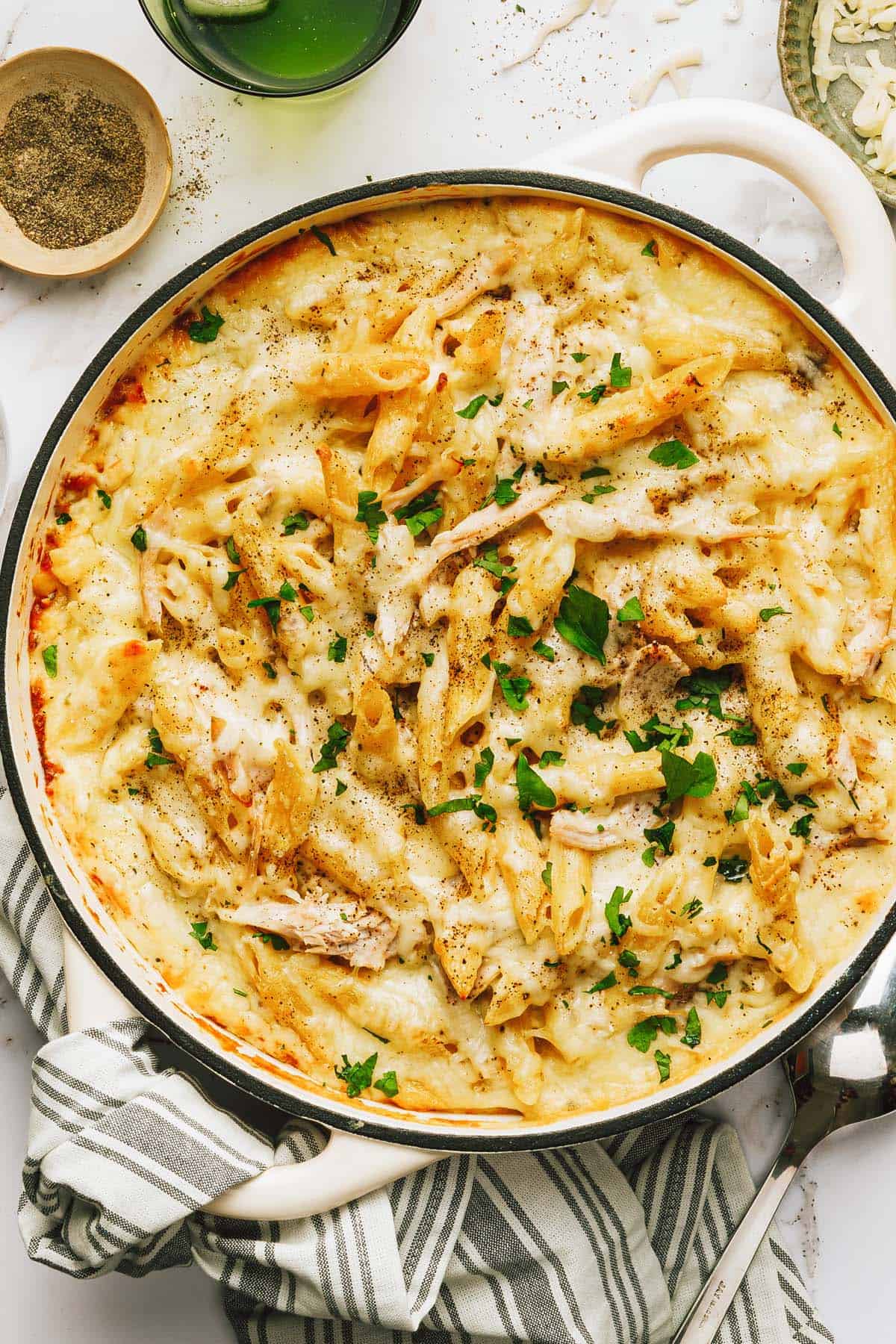 Large pan filled with creamy chicken alfredo pasta bake garnished with fresh parsley. 