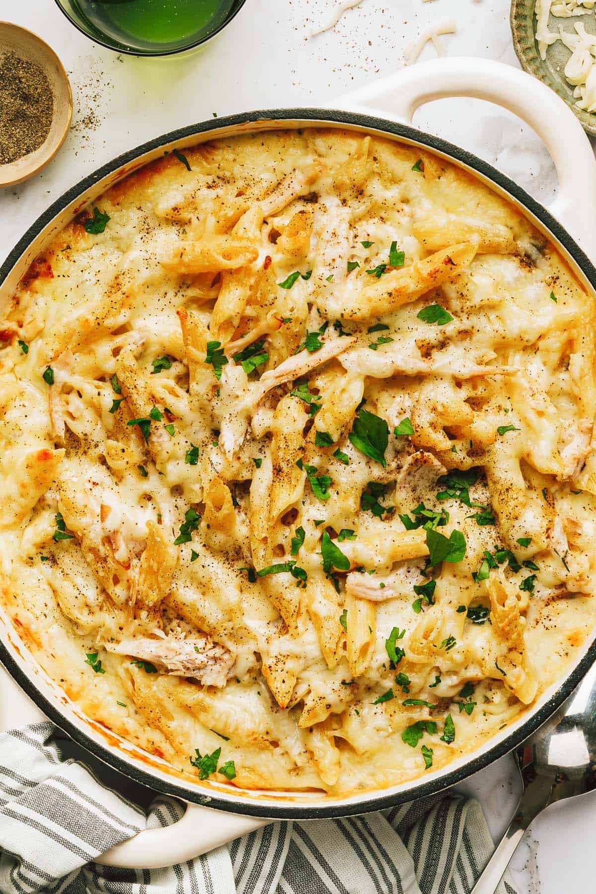 Large pan filled with creamy chicken alfredo pasta bake garnished with fresh parsley. 