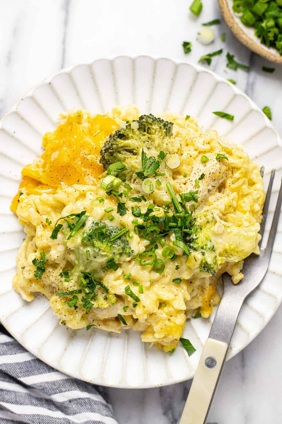 Cheesy chicken and broccoli casserole on a plate with fresh parsley. 