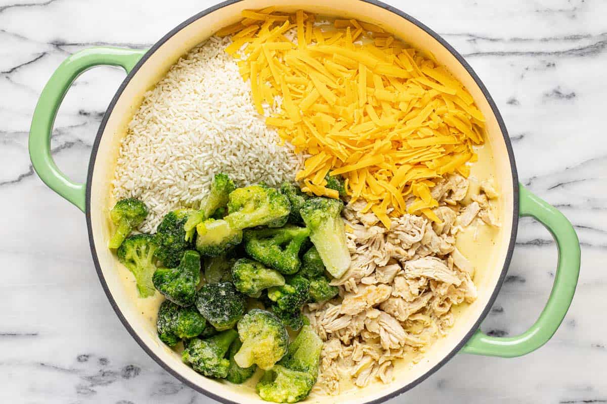 Rice, cheese, broccoli, and chicken added to a pan of cheese sauce. 