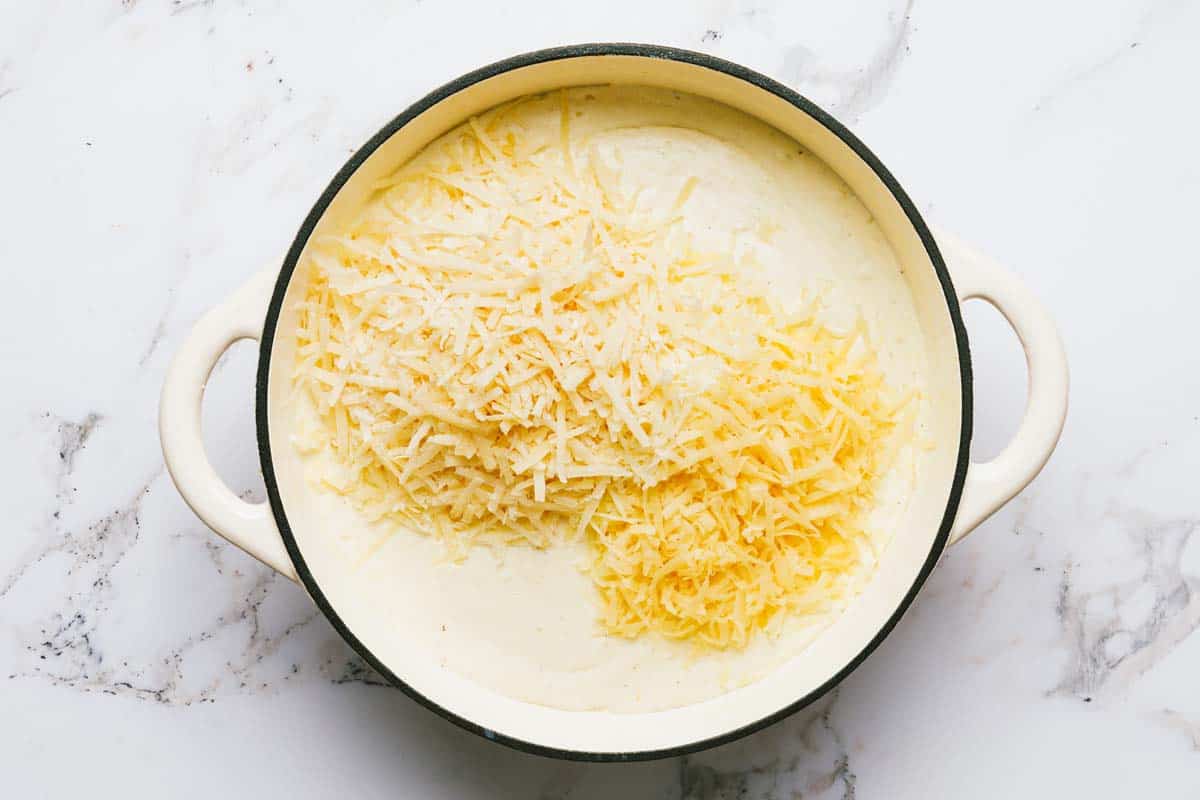 Large pan with cream sauce and shredded cheese. 