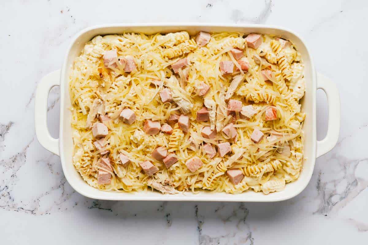 Baking dish filled with homemade chicken cordon bleu casserole topped with cheese. 