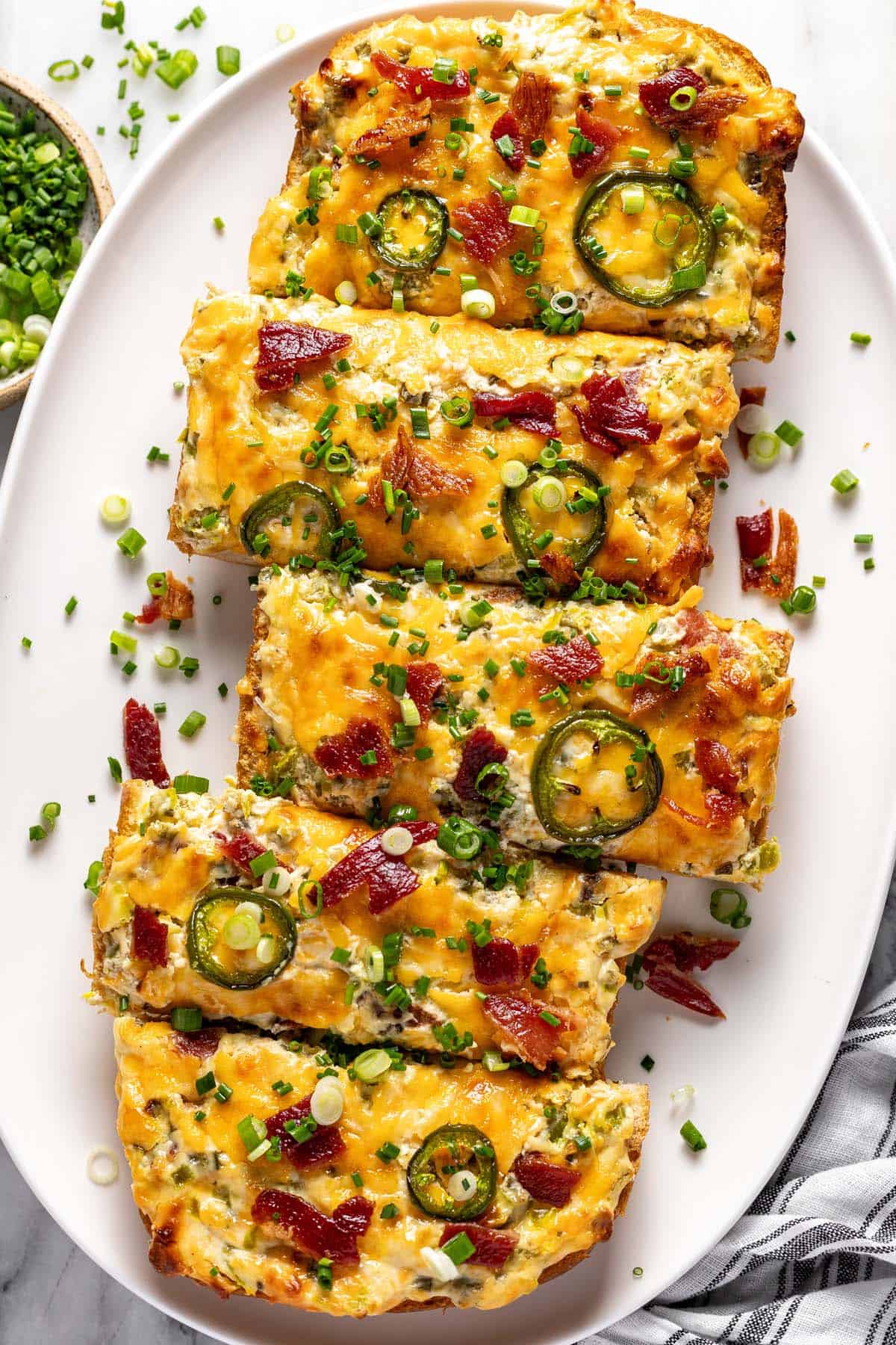 Jalapeno popper cheese bread garnished with green onions on a serving platter.