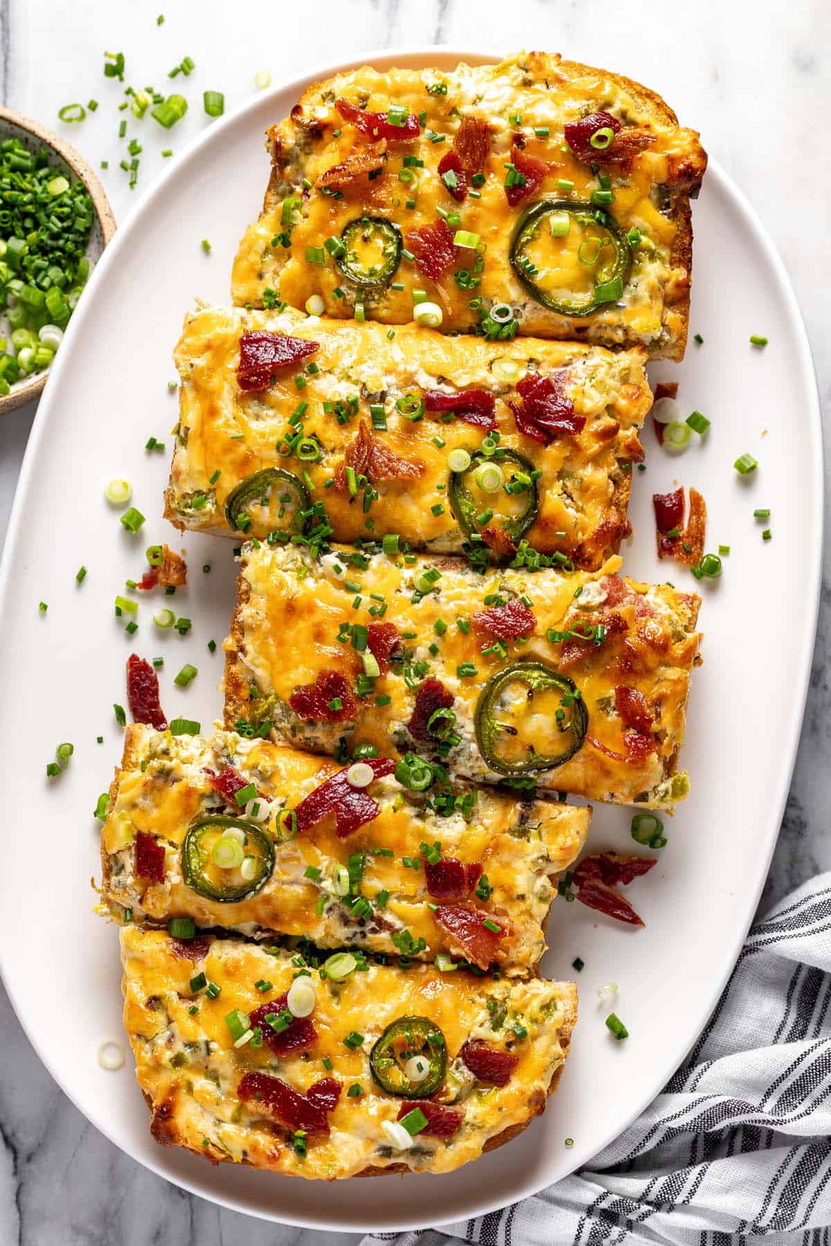 Jalapeno popper cheese bread garnished with green onions on a serving platter.