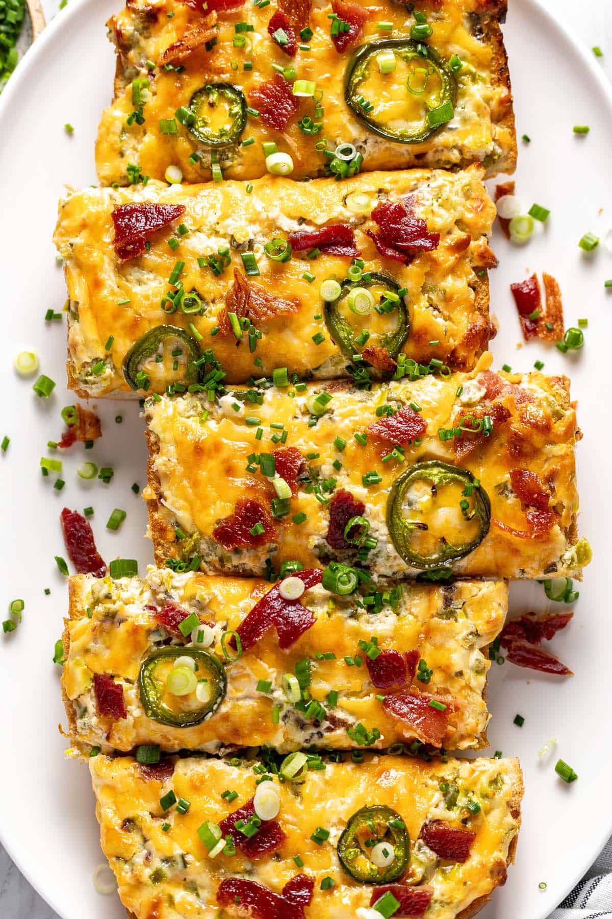 Jalapeno popper cheese bread garnished with green onions on a serving platter.