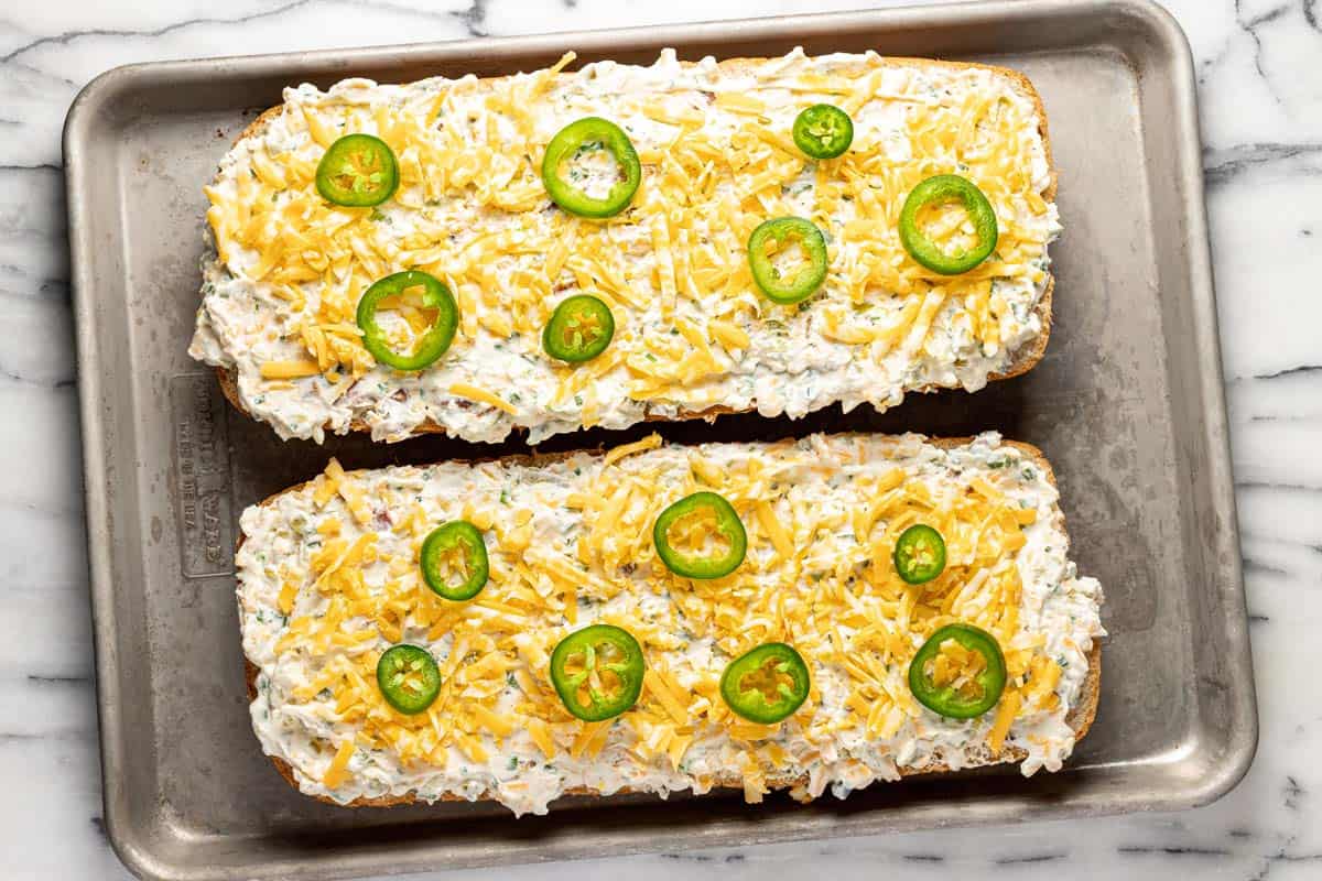 Shredded cheese and sliced jalapeno on top of jalapeno popper bread. 