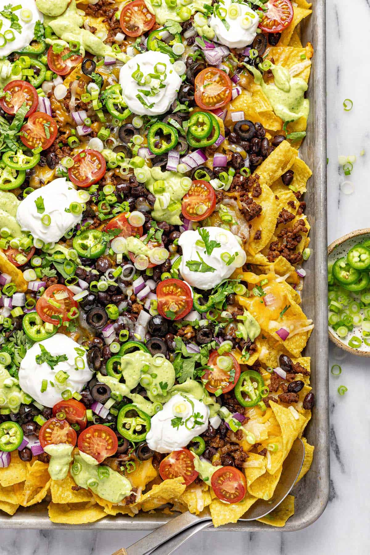 Close up of loaded nachos on a sheet pan. 