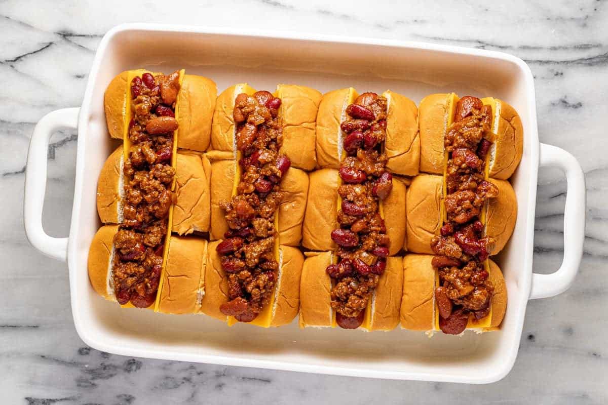 Cheesy hot dogs topped with chili in a baking dish. 