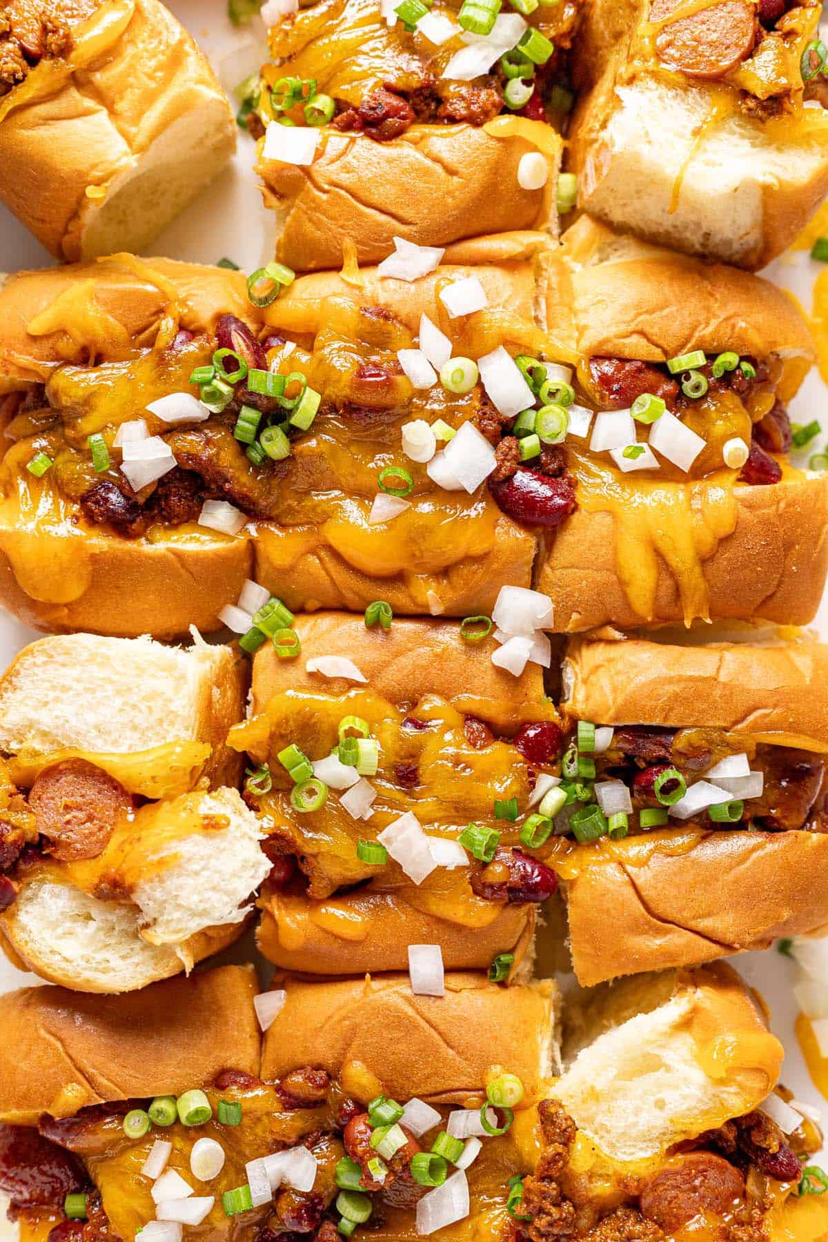 Close up shot of mini chili cheese dogs in a baking dish. 