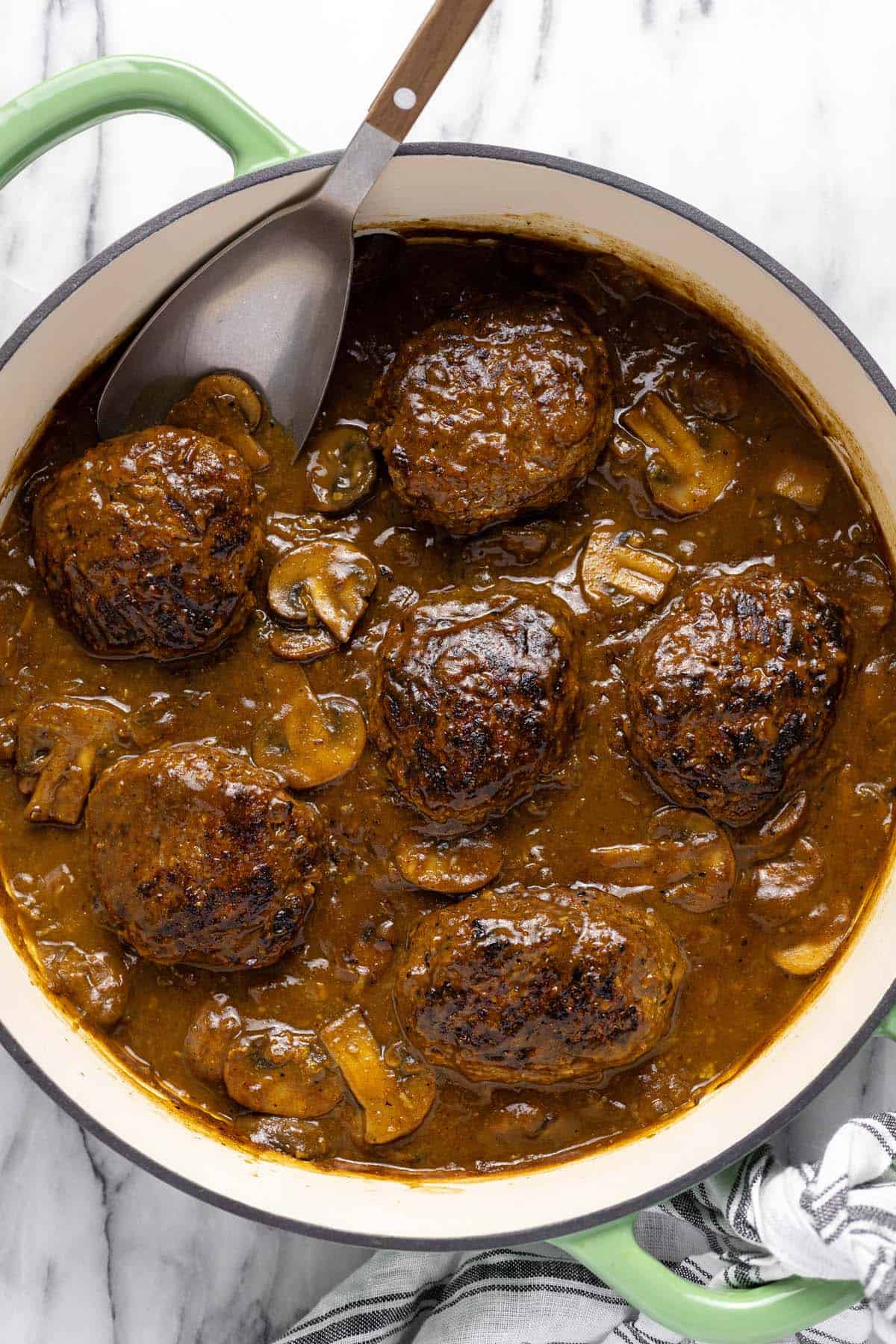 Salisbury steak in a creamy mushroom sauce in a large pan. 