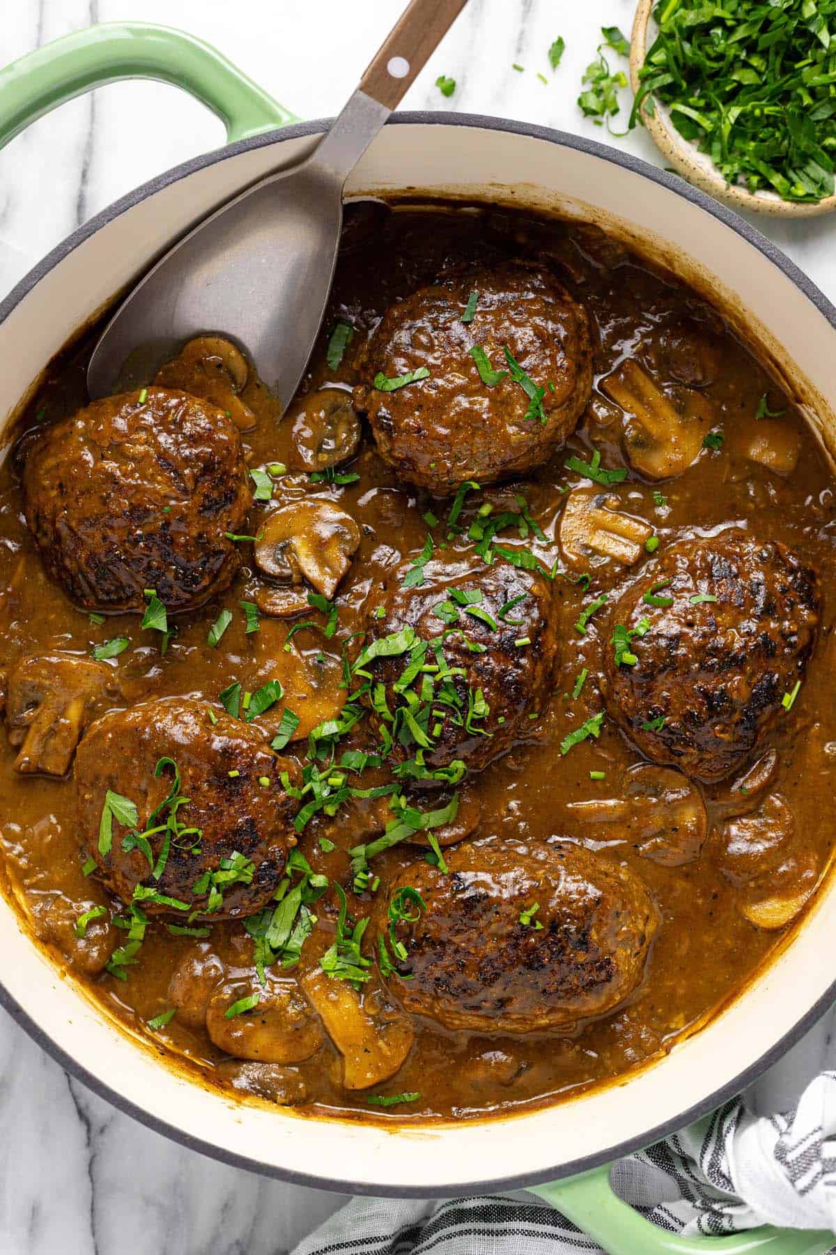 Large pan filled with homemade Salisbury steak in a mushroom gravy. 