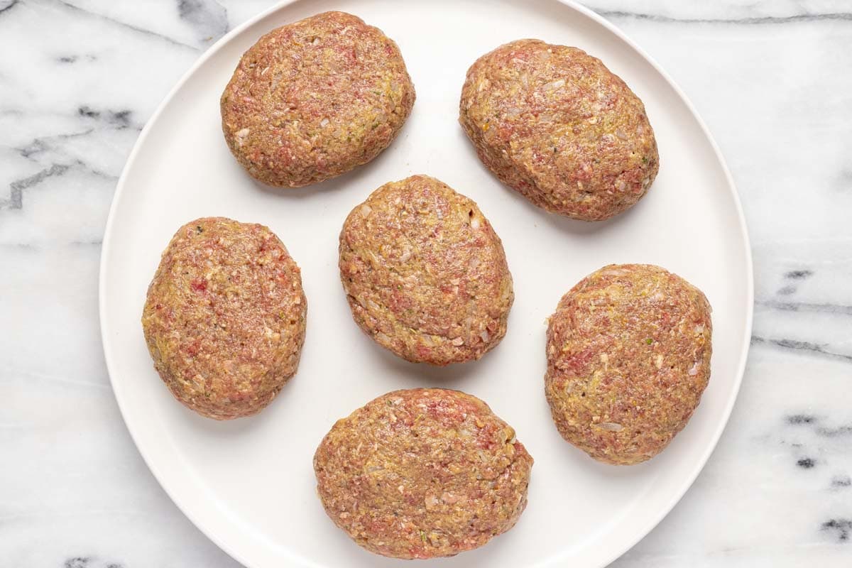 Six Salisbury steak patties on a large plate. 