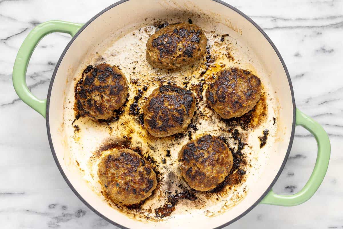 Salisbury steak sauteed in a large pan. 