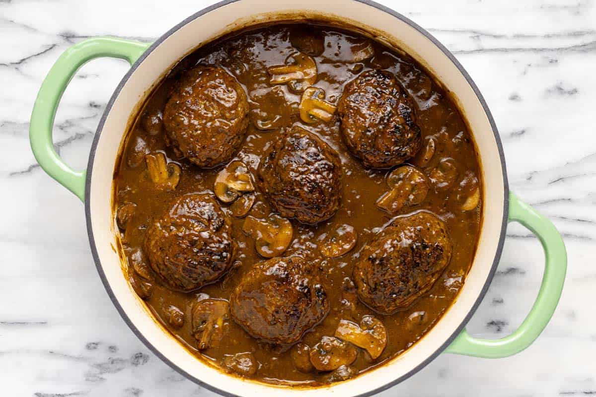 Homemade Salisbury steak in a mushroom sauce in a large pan. 