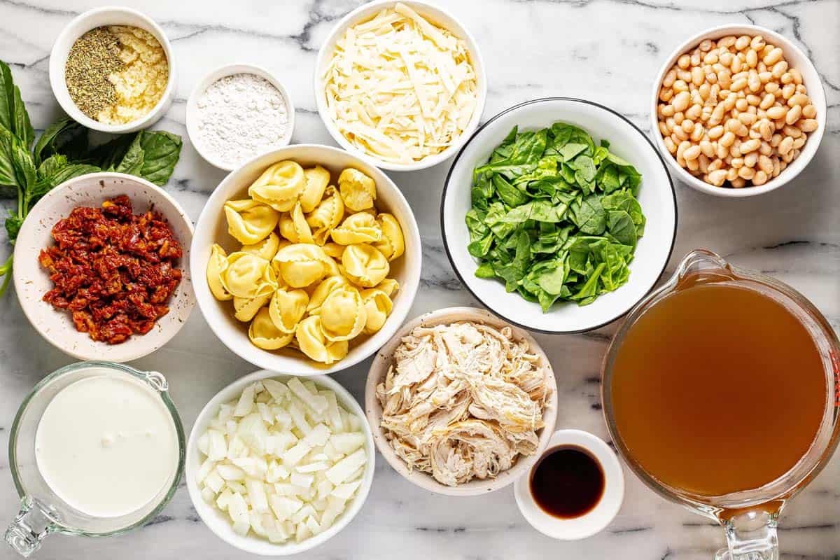 Bowls of ingredients to make creamy Tuscan chicken tortellini soup. 