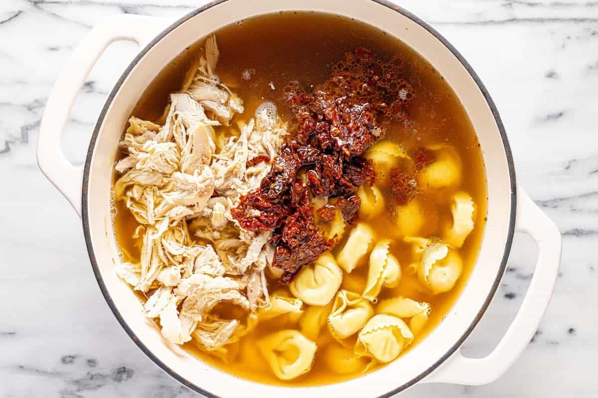 Shredded chicken, sun-dried tomatoes, and tortellini in broth for Tuscan soup. 