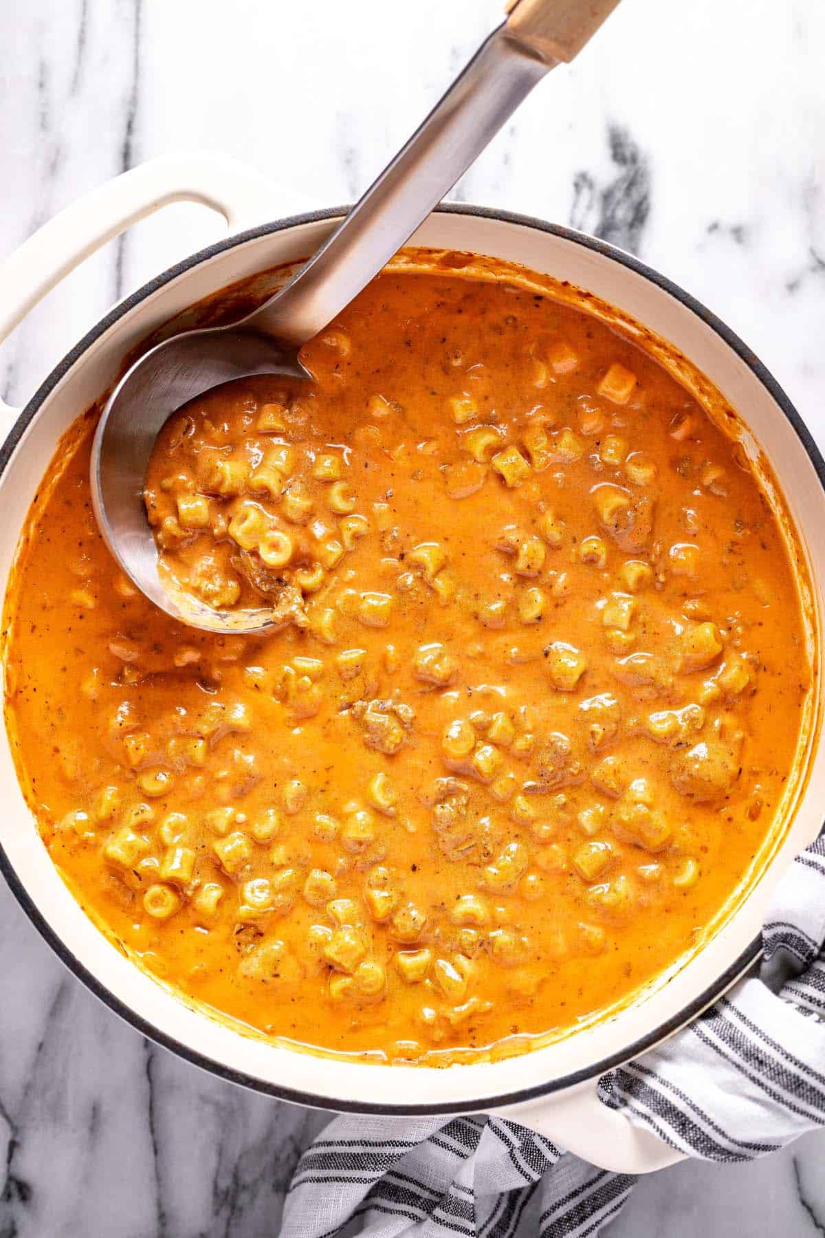 Large pot filled with creamy tomato soup with ground beef and noodles. 