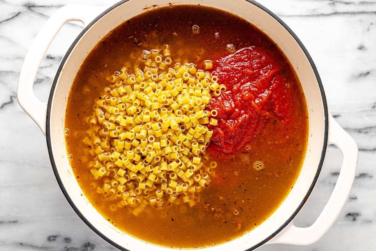 Large pot filled with ground beef, tomato sauce, broth, and noodles. 