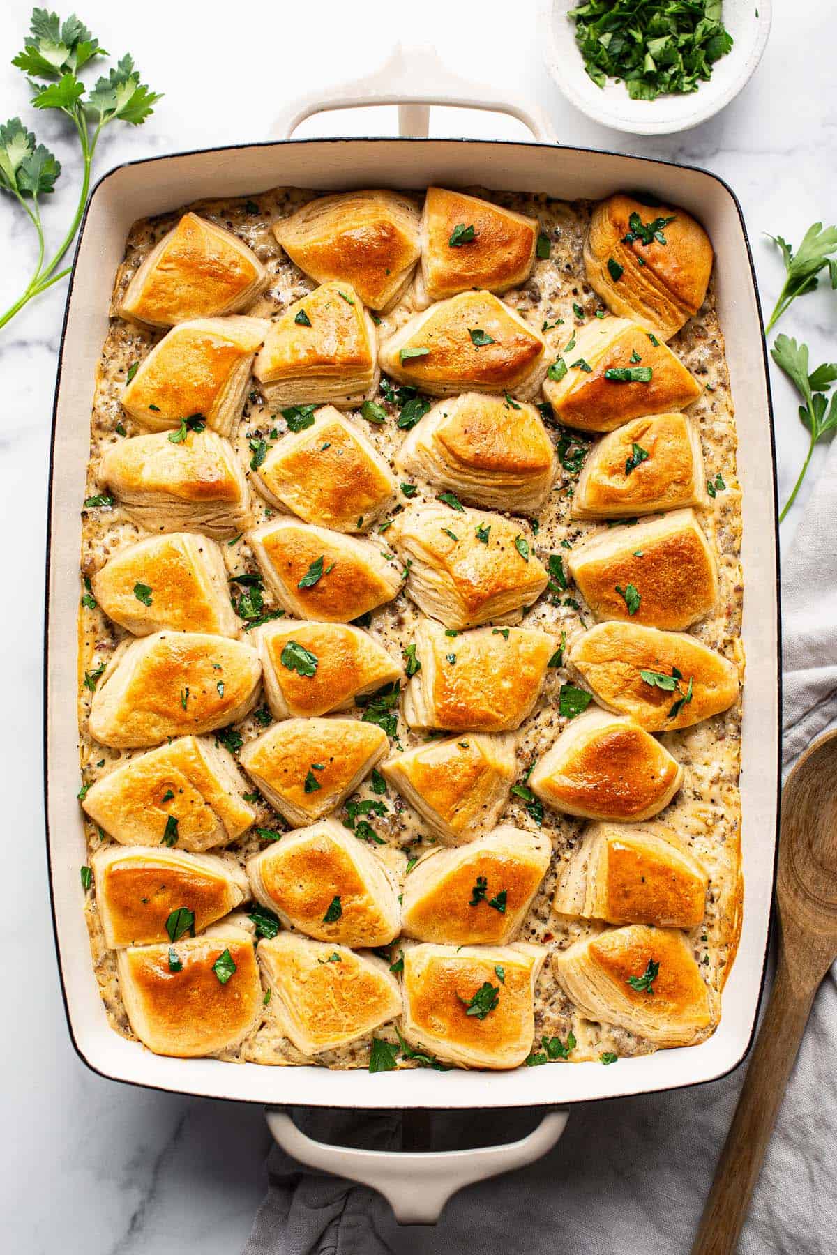 Large baking dish filled with biscuits and gravy casserole garnished with parsley. 