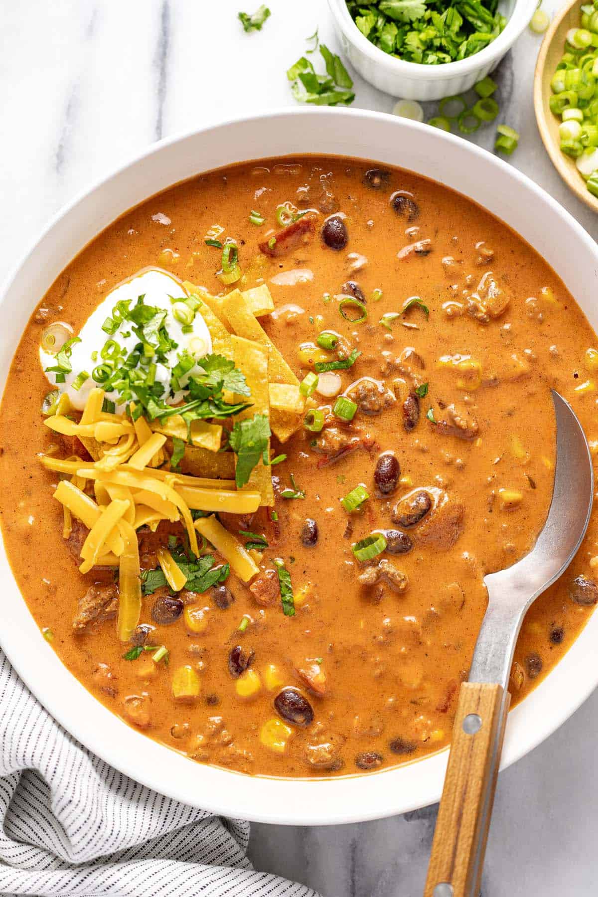 Creamy taco soup in a bowl topped with tortilla strips and cheese. 