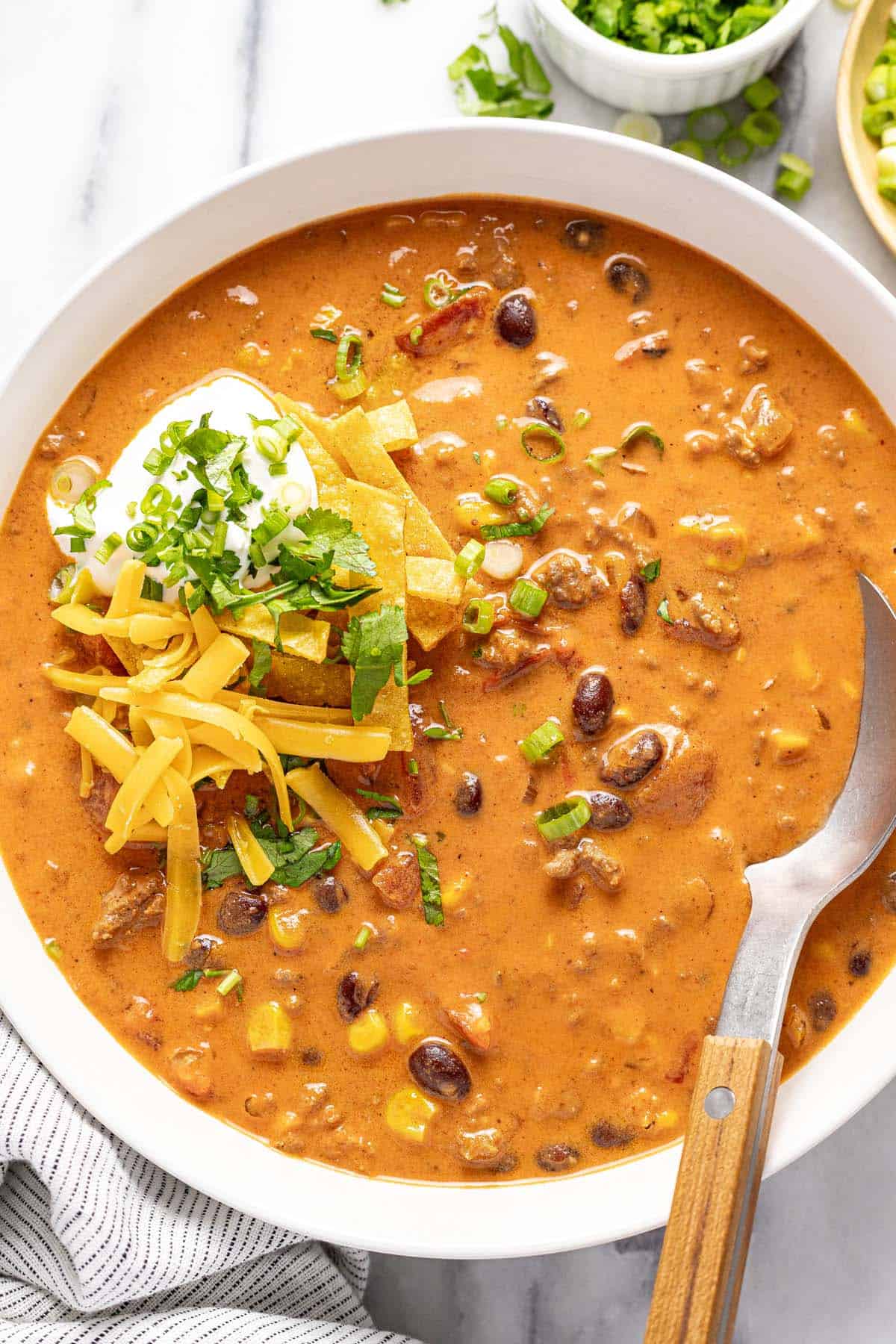 Creamy taco soup in a bowl topped with tortilla strips and cheese. 