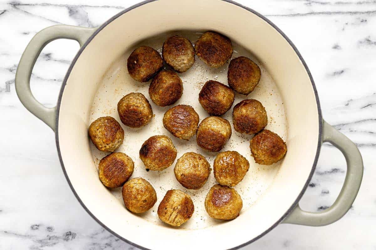 Seared meatballs in a large pot. 