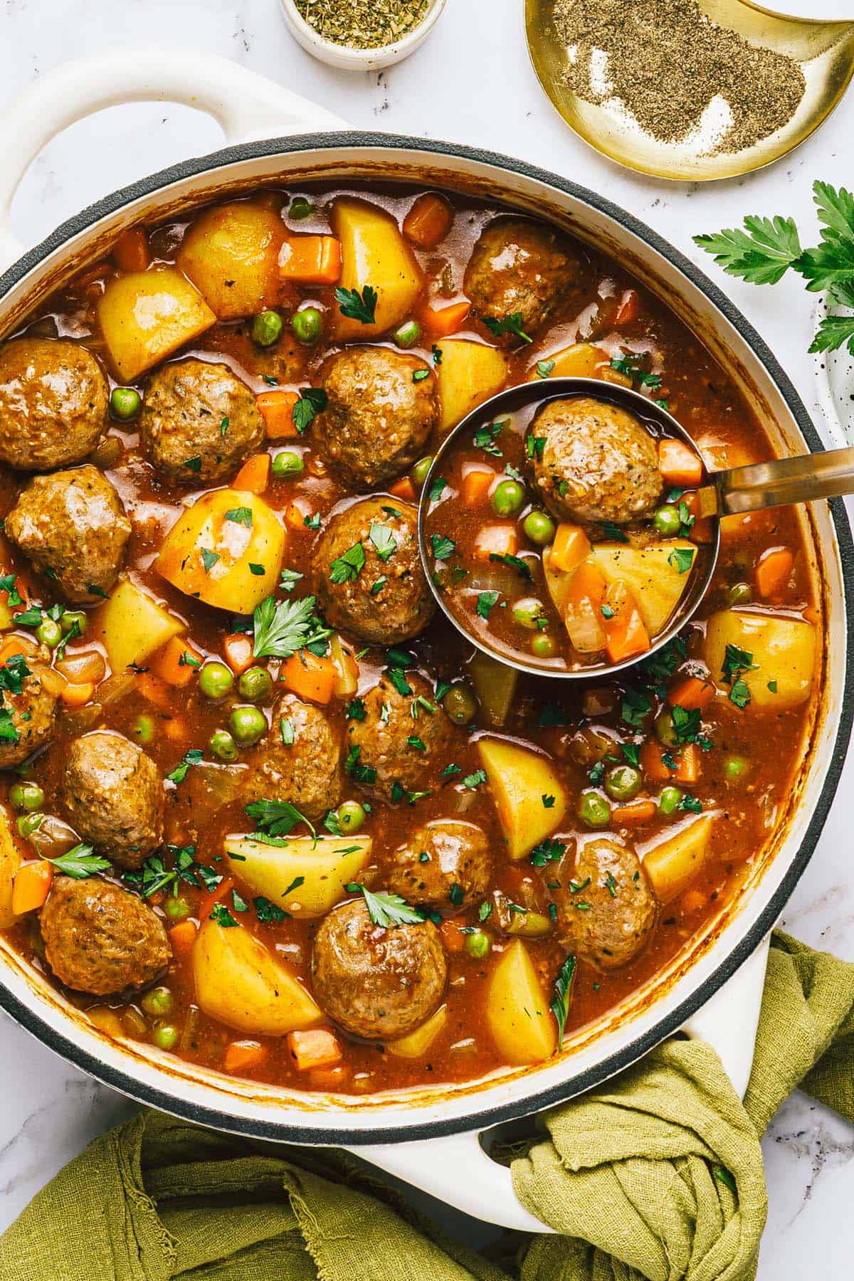 Large pot of meatball stew with a ladle. 