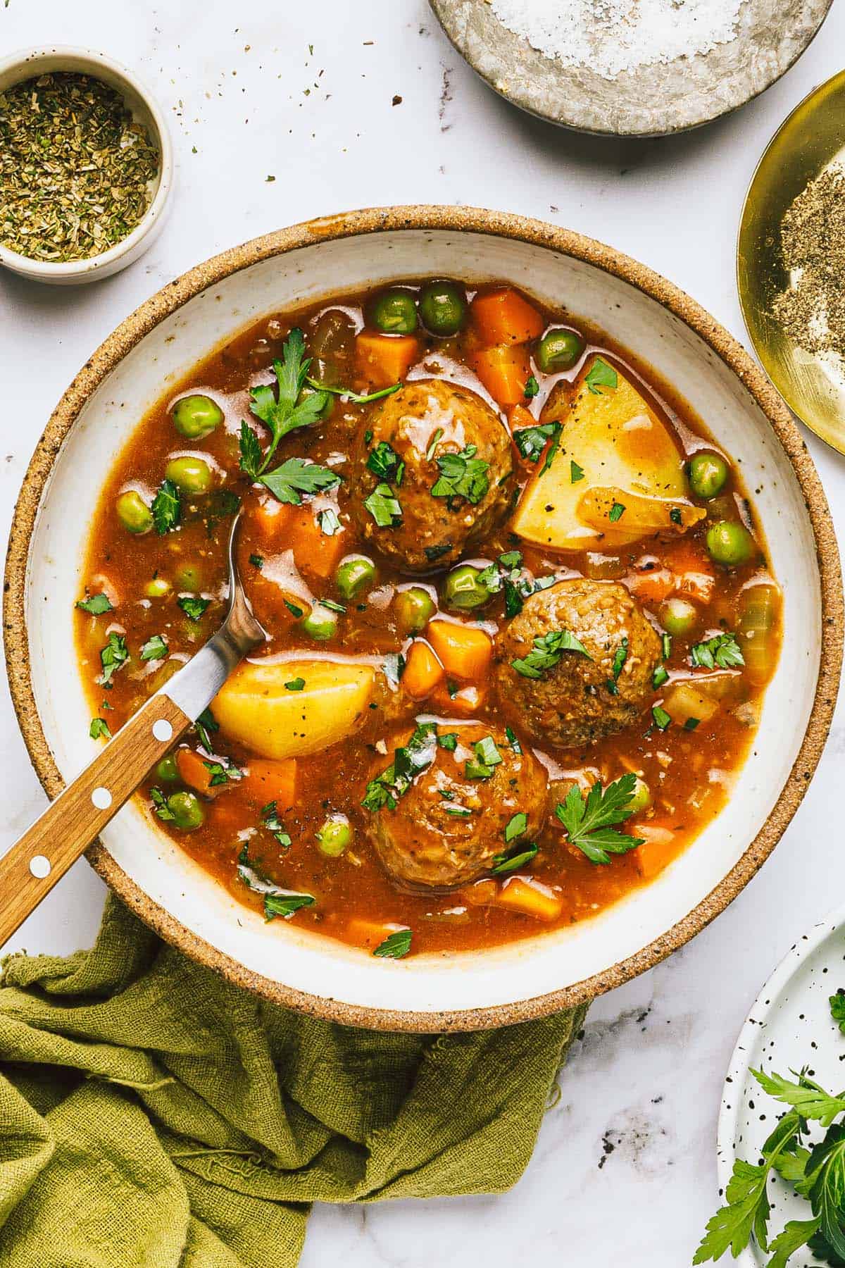 Bowl of meatball stew garnished with fresh parsley. 