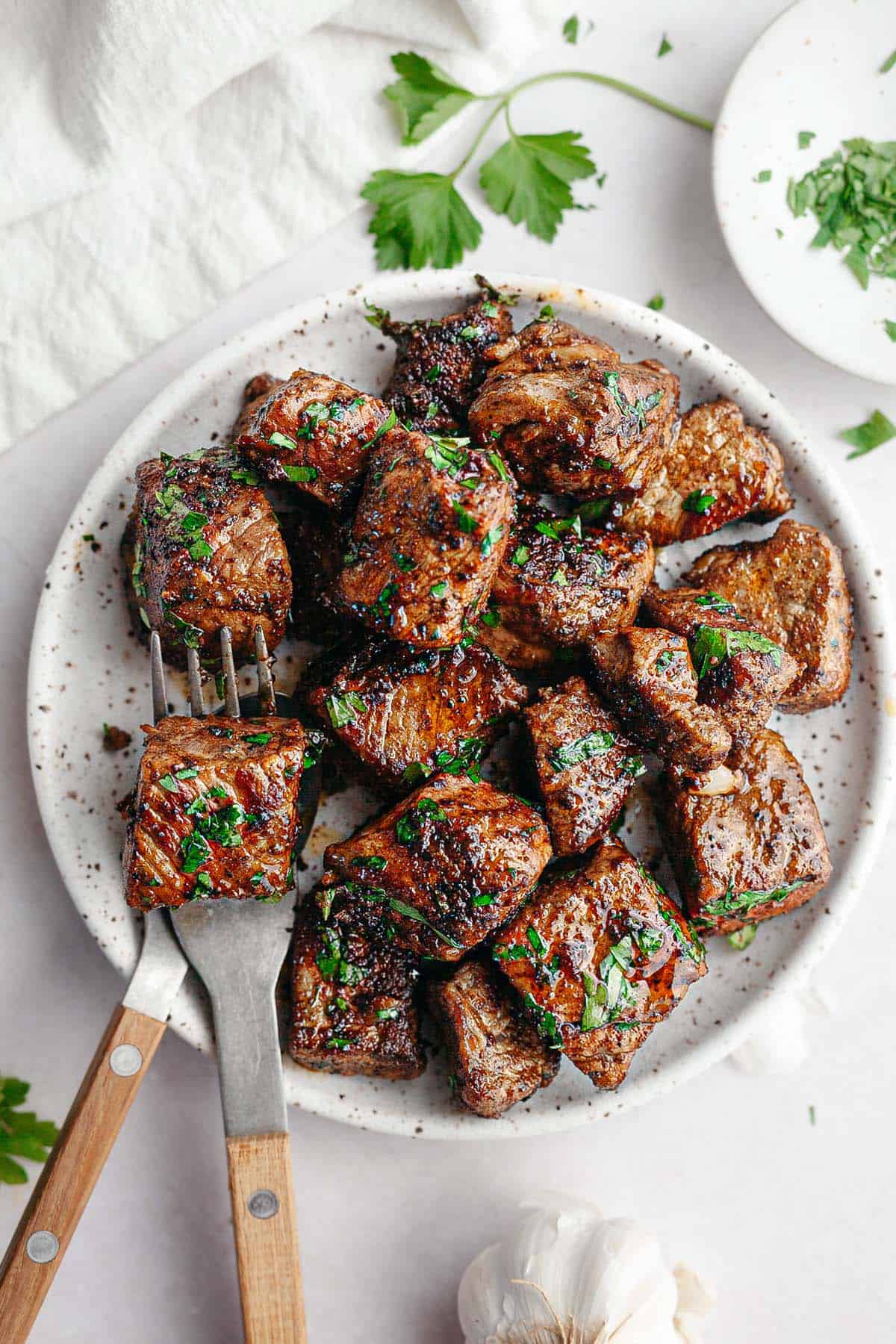 Plate with garlic butter steak bites garnished with fresh parsley. 