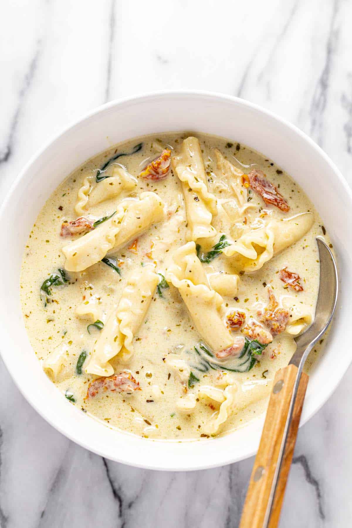 Bowl of white chicken lasagna soup with a spoon. 