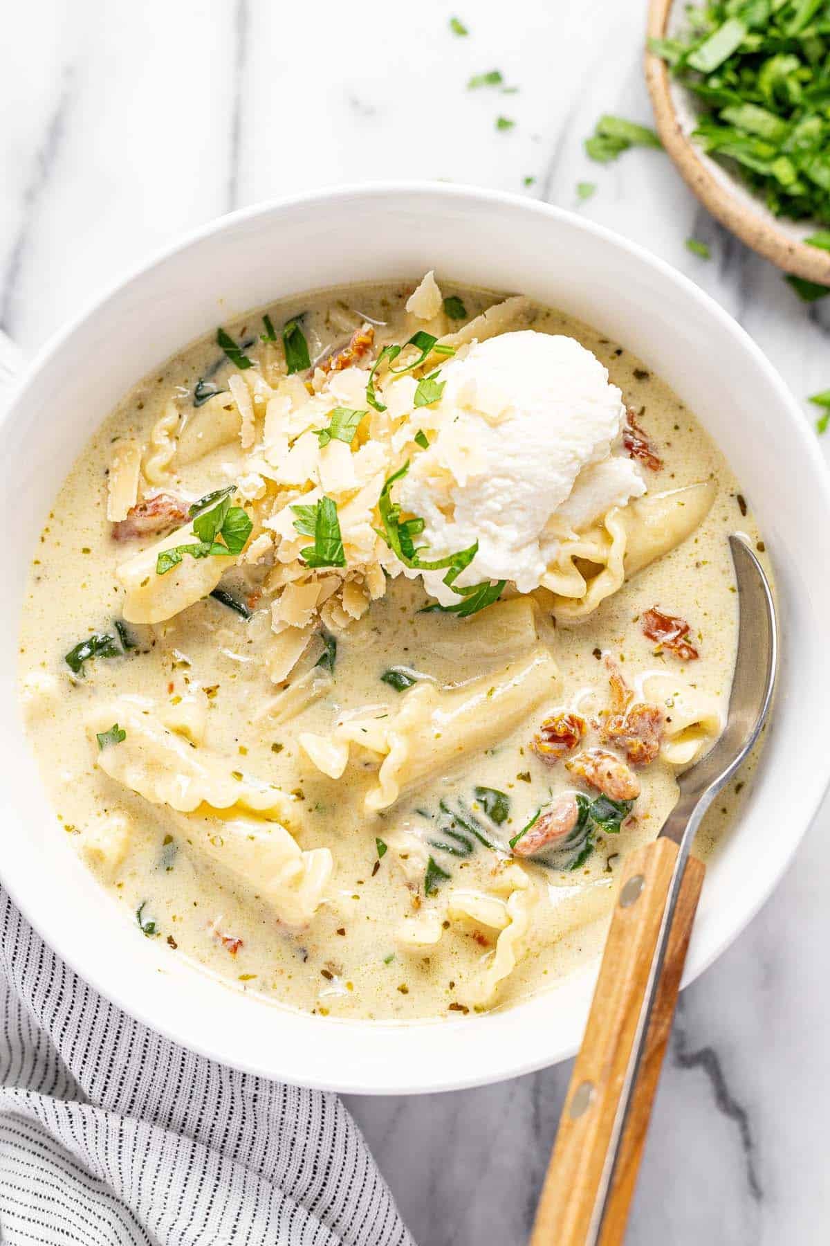 Ricotta and Parmesan cheese on top of creamy white lasagna soup. 