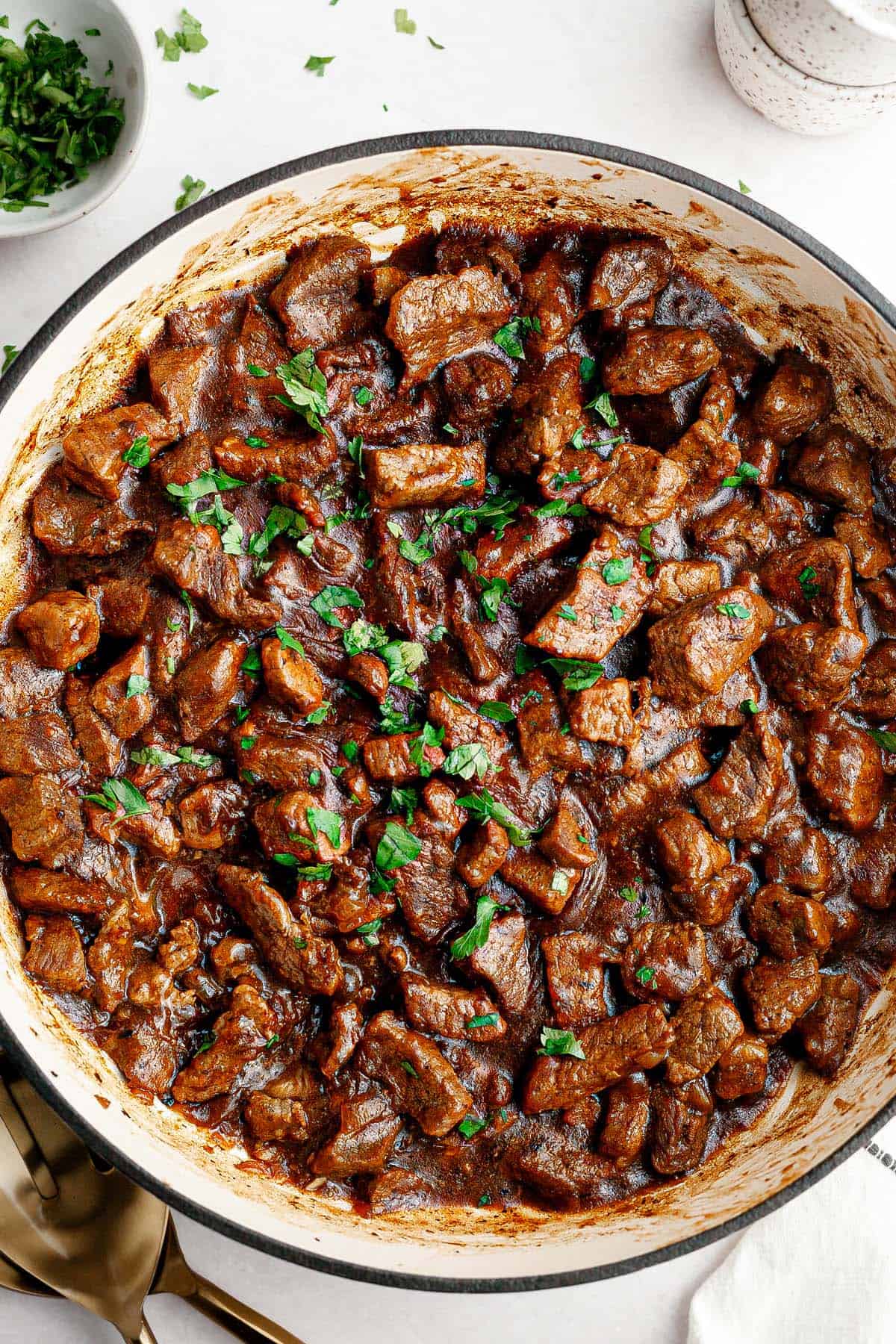 Large pan of beef tips and gravy recipe garnished with fresh parsley. 