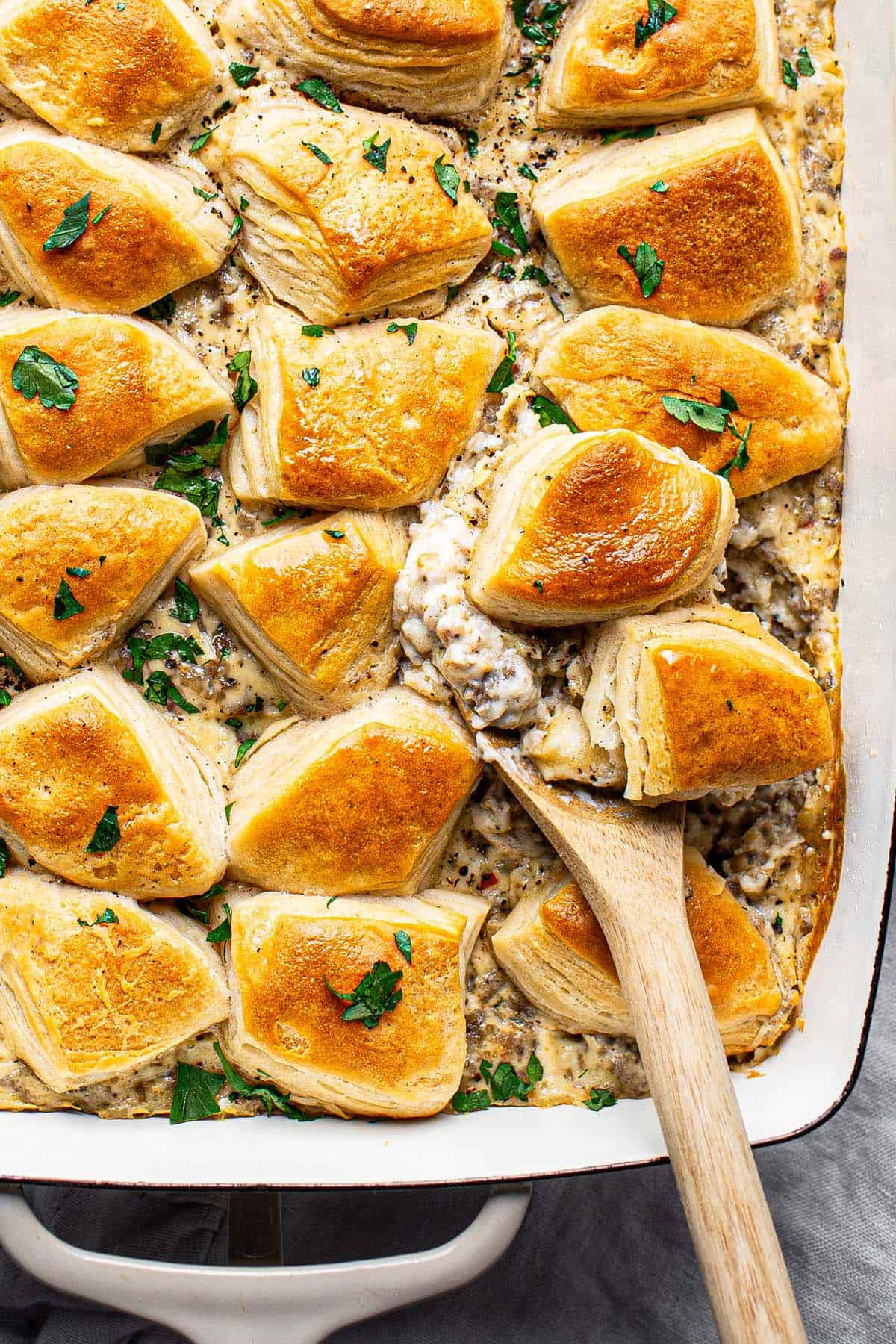 Close up shot of a spoon scooping biscuits and gravy casserole. 