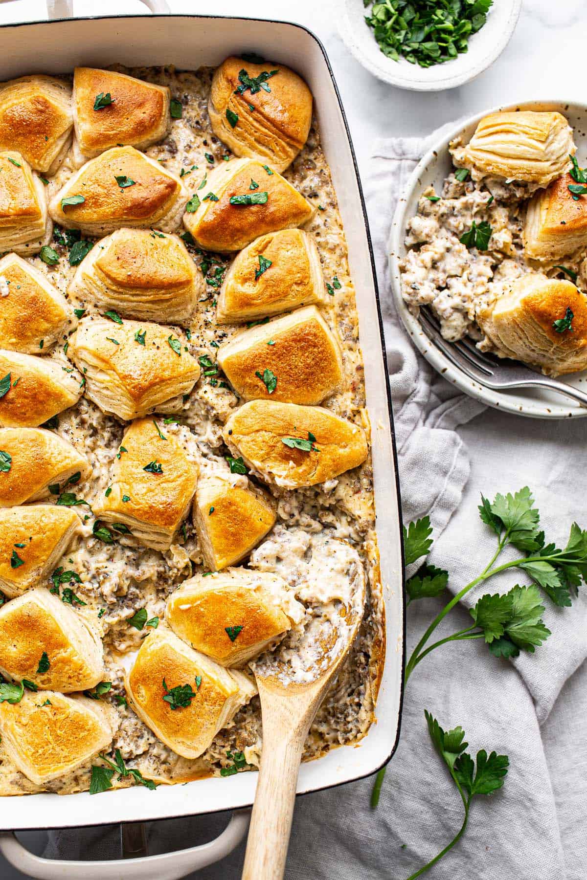 A large pan of biscuits and gravy casserole garnished with parsley. 