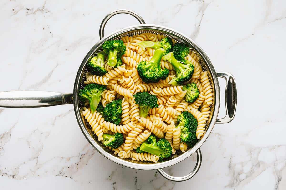 Pasta in a strainer with broccoli. 