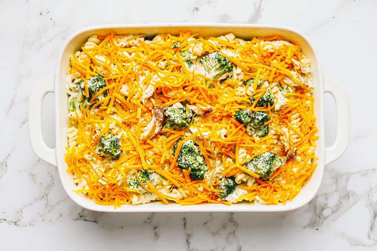 Cheesy broccoli chicken bake in a large pan topped with shredded cheese. 