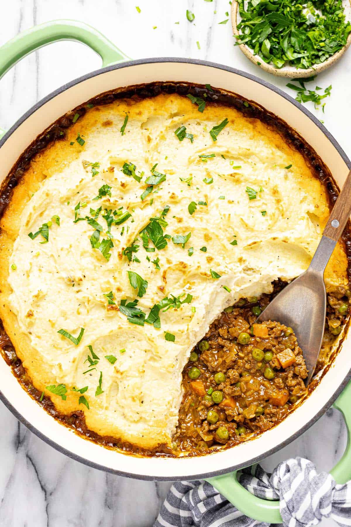 Large pan filled with homemade cottage pie garnished with parsley. 