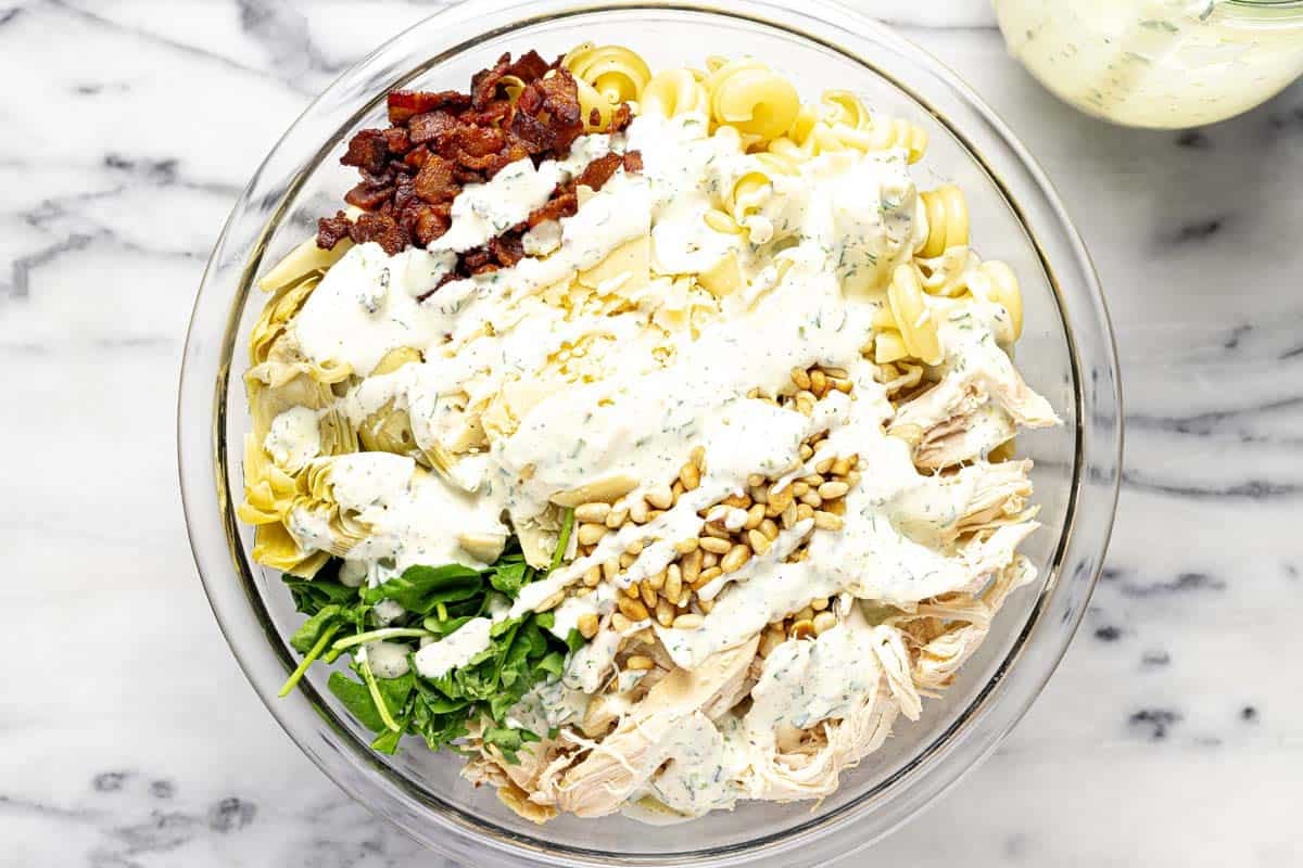 Creamy dressing drizzled over a bowl of creamy chicken pasta salad. 