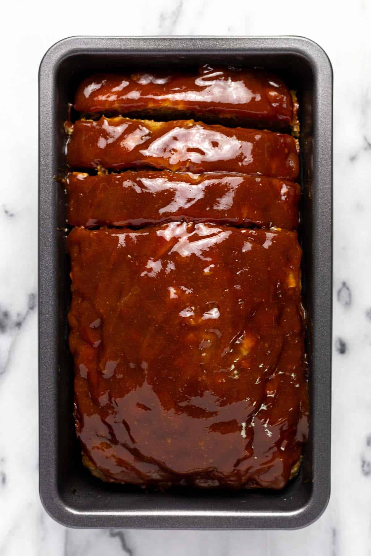 Freshly baked meatloaf sliced in a loaf pan. 