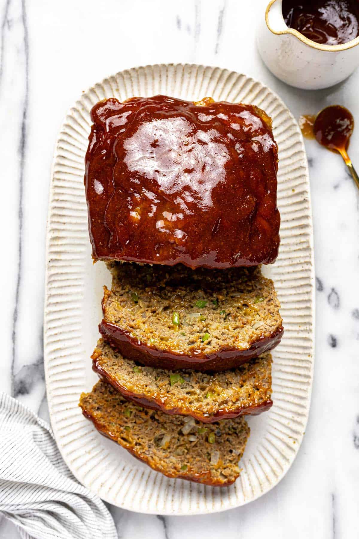 Sliced meatloaf topped with glaze on a white serving platter.