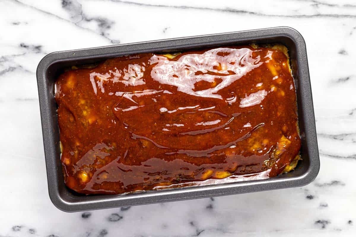 Loaf pan with glazed meatloaf in it. 