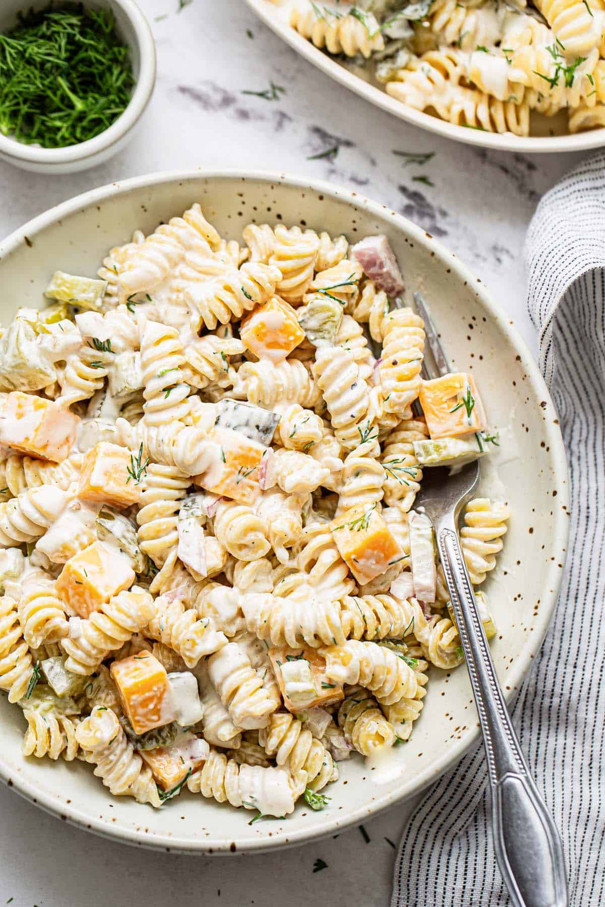Close up of dill pickle pasta salad in a bowl with a fork. 
