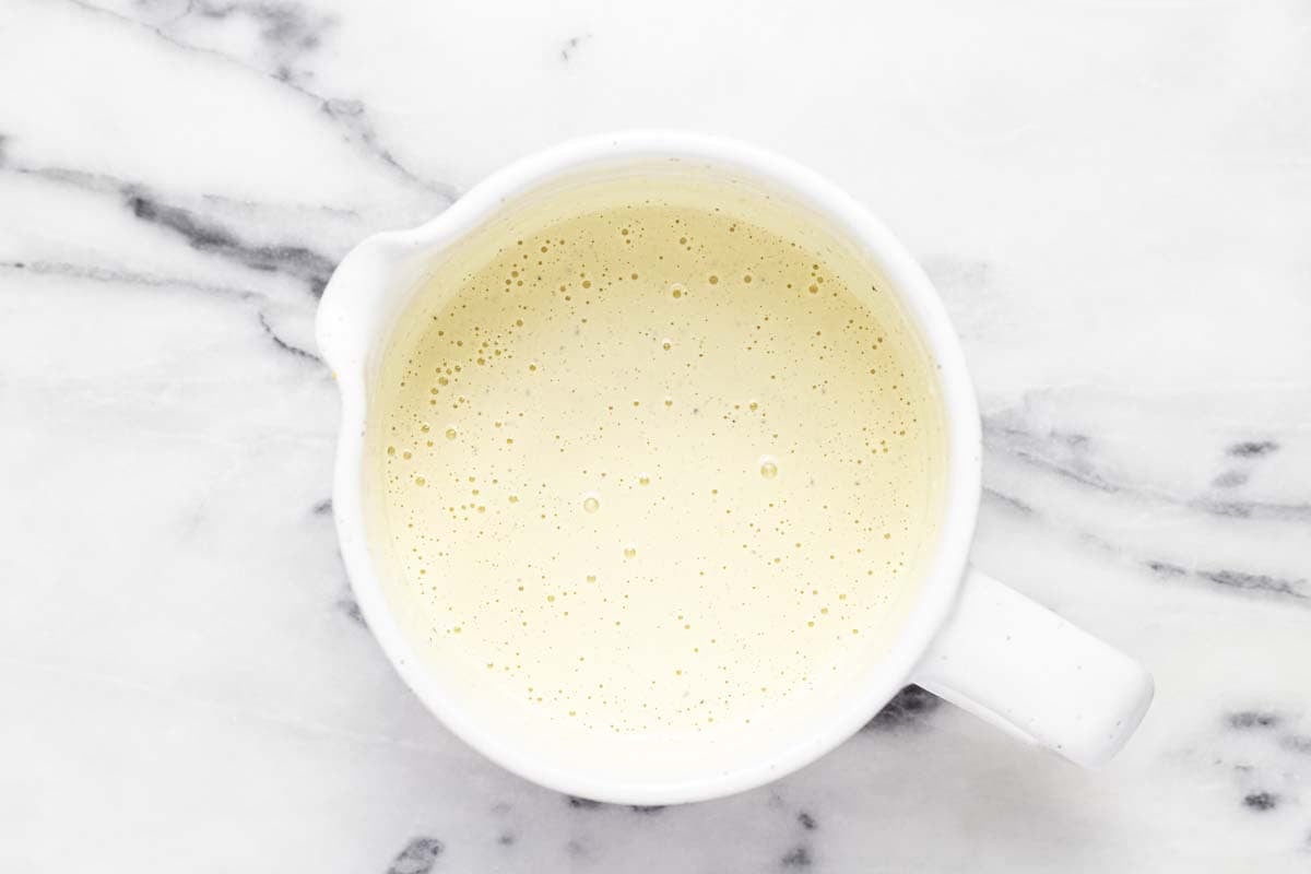 Mixing cup with creamy potato salad dressing in it. 
