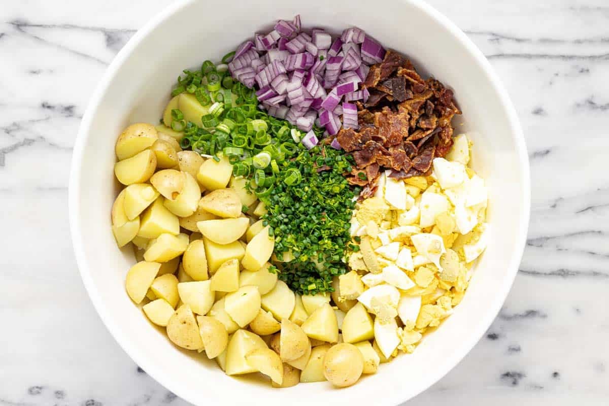 Large bowl filled with ingredients to make easy potato salad. 