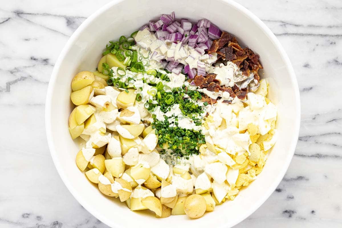 Creamy dressing drizzled over potato salad ingredients. 