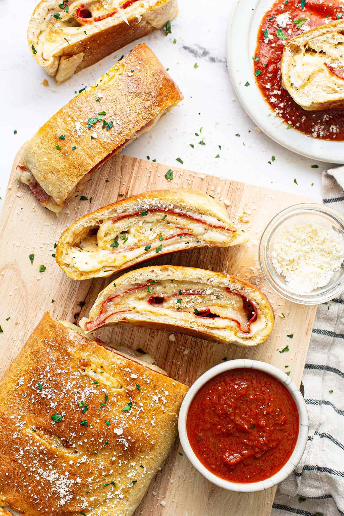 Cutting board with slices of stromboli garnished with Parmesan cheese. 