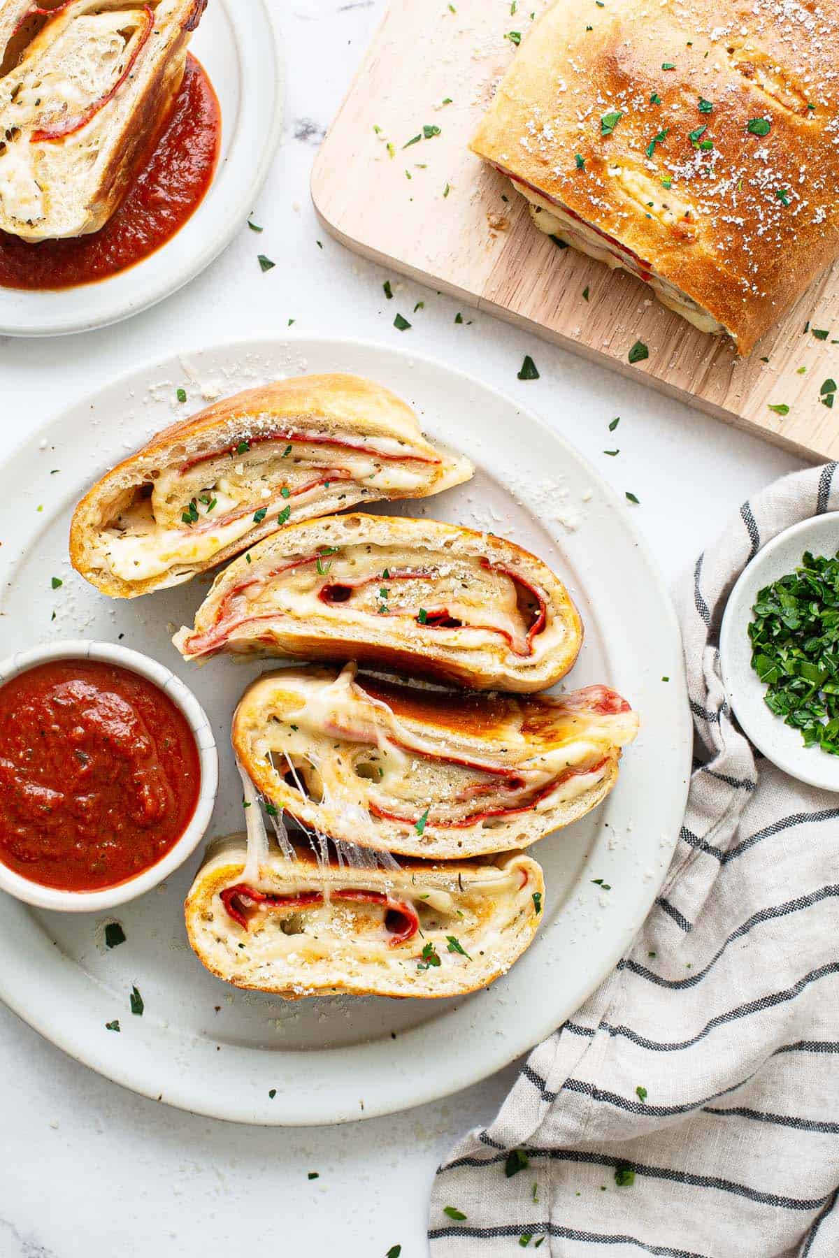 Sliced pepperoni stromboli with a bowl of pizza sauce.